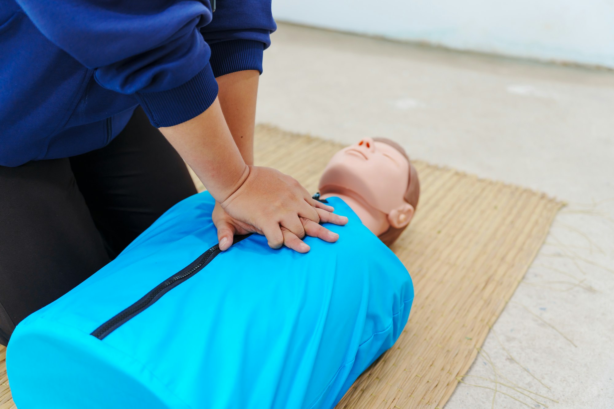 A woman performs chest compressions on a dummy during a CPR training class